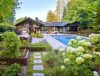 Luxurious backyard garden with lush greenery, stone path, and a modern pool next to a stylish home exterior