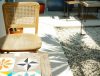 Sunlit wooden chair and colorful tiled table in a tranquil outdoor patio with white pebbles and shadows