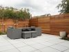 Modern patio with grey outdoor furniture, wooden fence, and potted plants, perfect for relaxation and entertaining