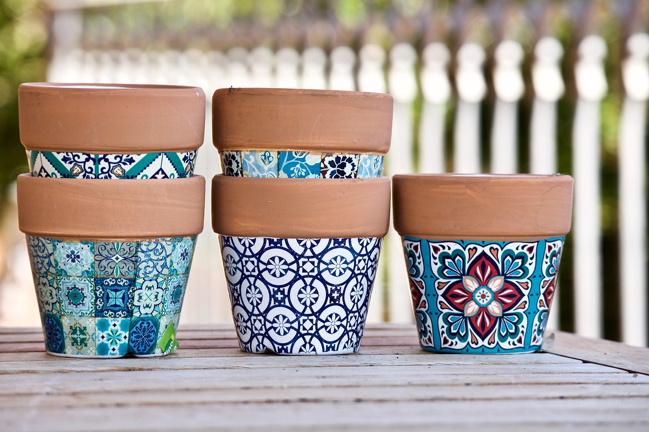 A collection of terracotta flower pots with decorative, colourful tile-patterned designs in shades of blue, teal, and red