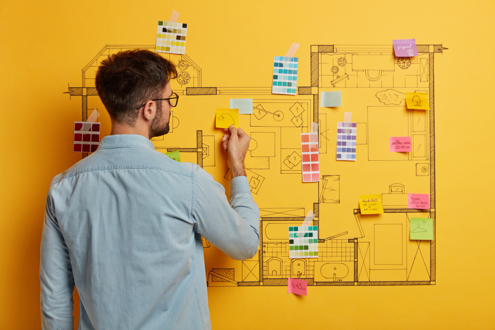 A man creatively arranges colorful post-it notes on a wall, forming a unique design or image
