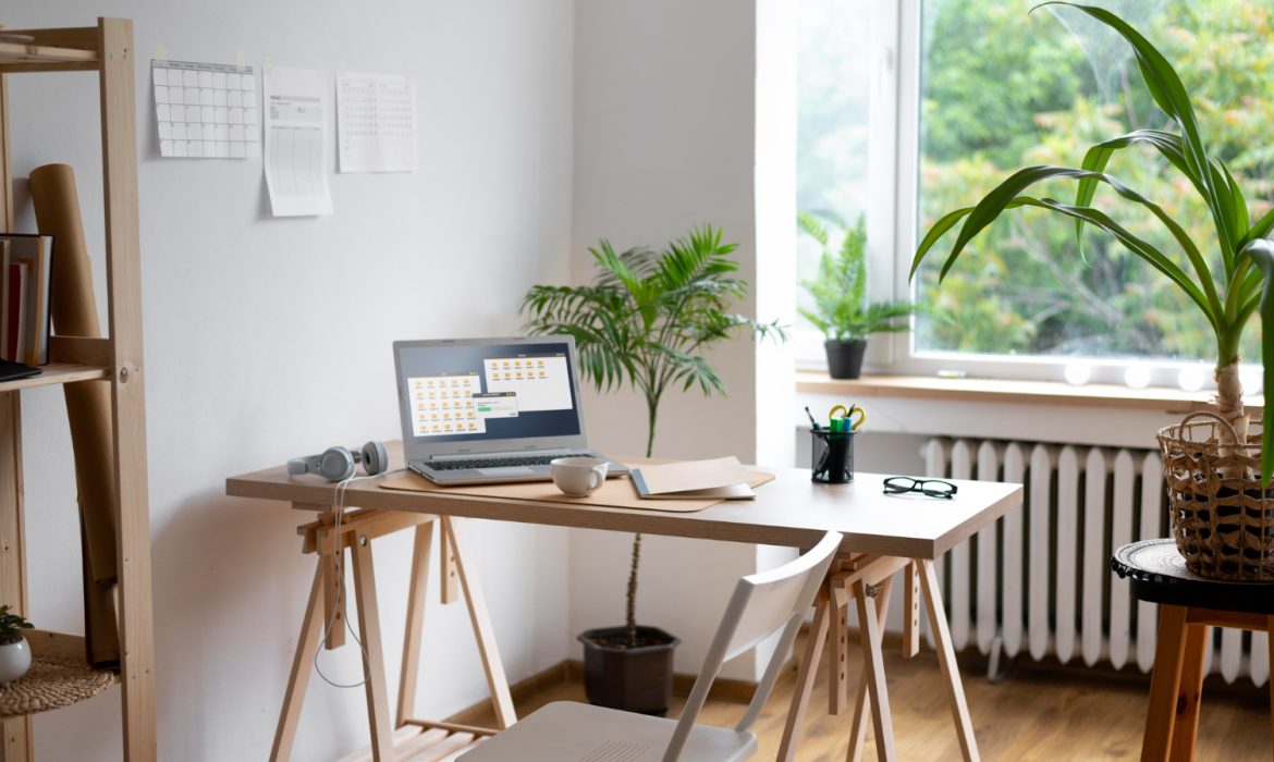 A desk featuring a laptop and a small green plant beside it, creating a workspace atmosphere